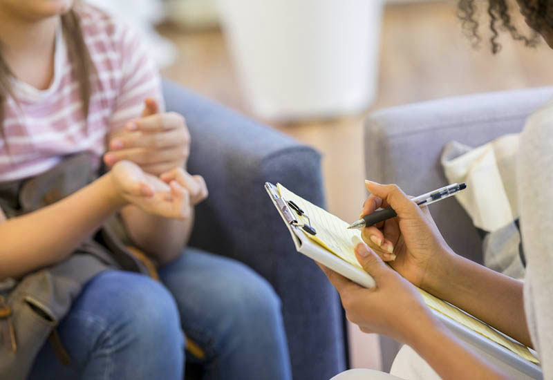 Mental Health Professional Takes Notes During Session in-person therapy